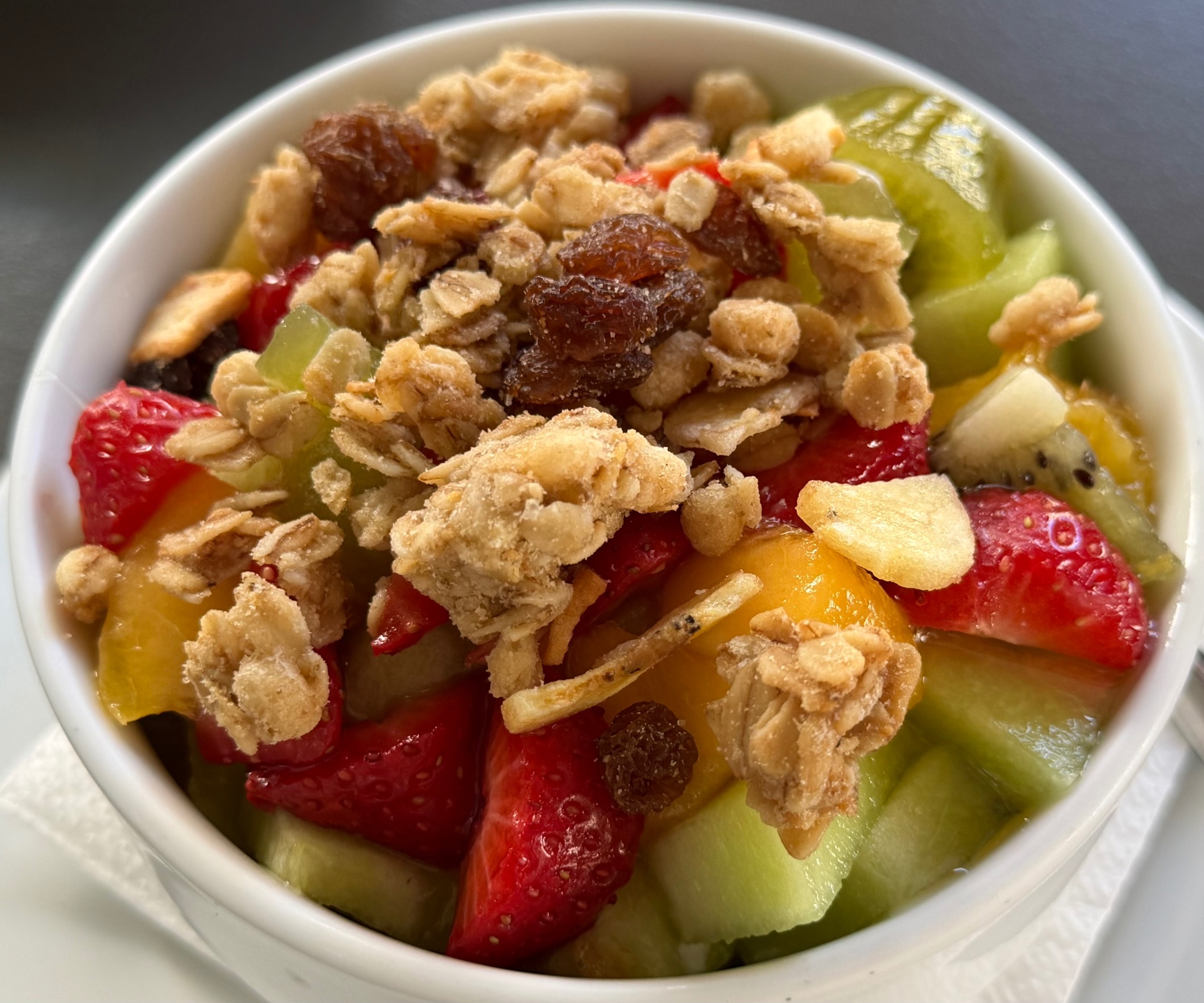 Fresh fruit bowl with strawberries, kiwi, melon and homemade granola — served at breakfast