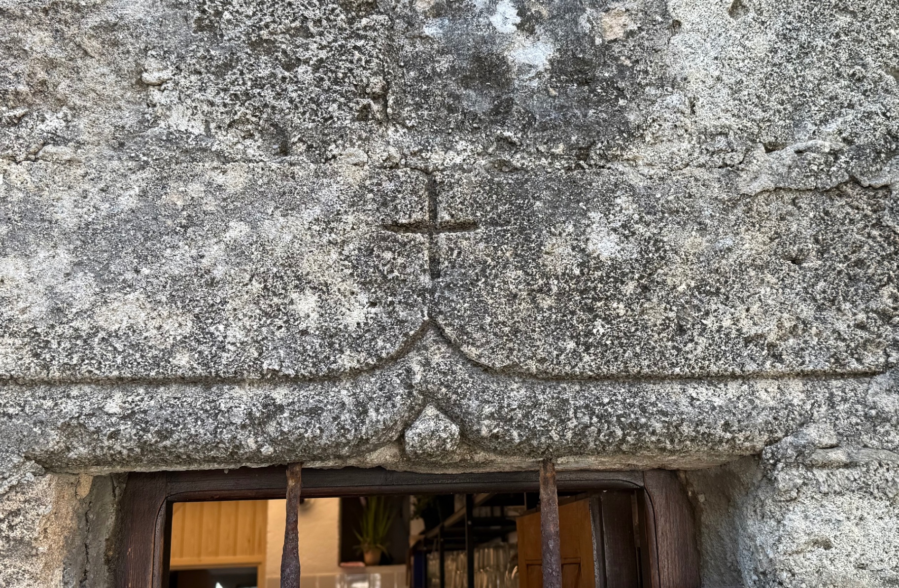 A cross incised into the stone directly above the small window