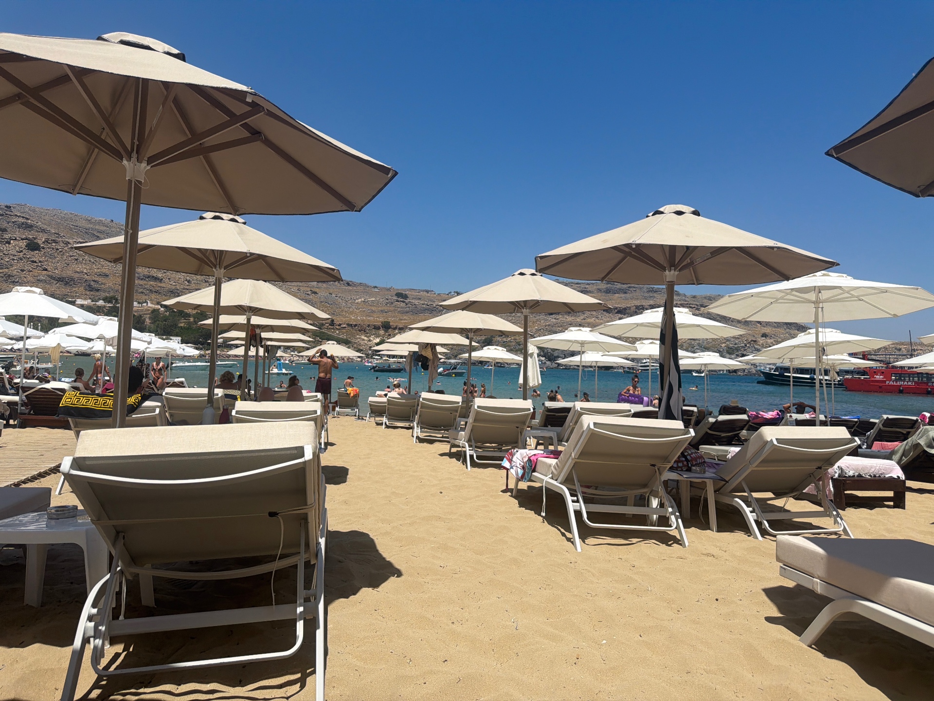 Soft sandy Pallas Beach in Lindos with white sunbeds and parasols