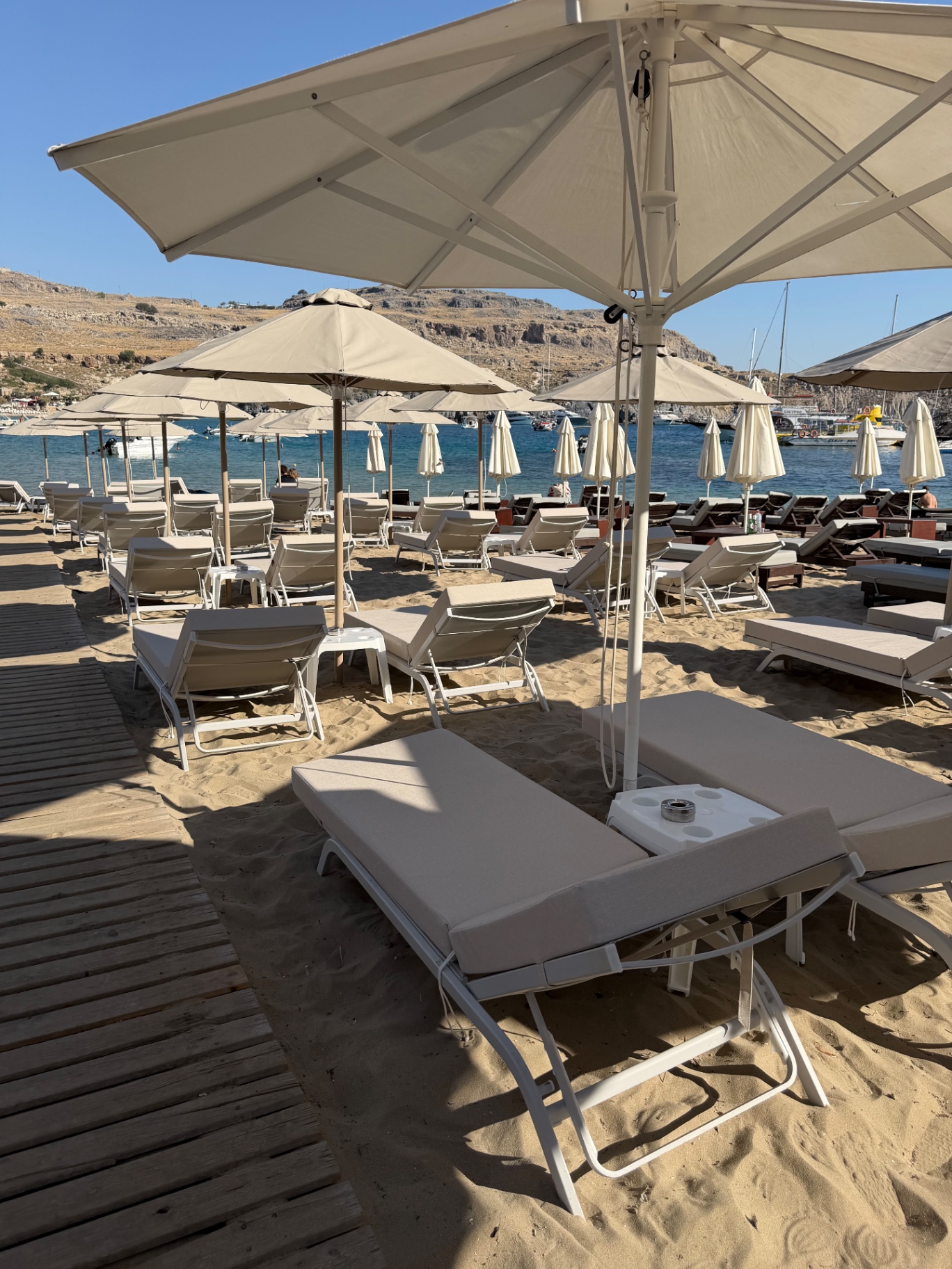 Sunbeds and a white parasol on the soft sand of Pallas Beach in Lindos